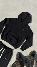 Finesse Air Cotton Hoodie noir au sol, packshot brut avec pieds du photographe visibles.