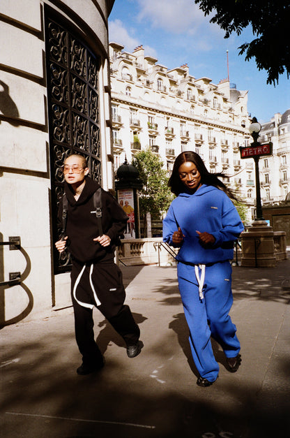 Un homme en Air Cotton noir et une femme en Air Cotton bleu courant dans une rue.