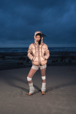 Femme de face dans les dunes portant la Finesse Alive Puffer Jacket beige.