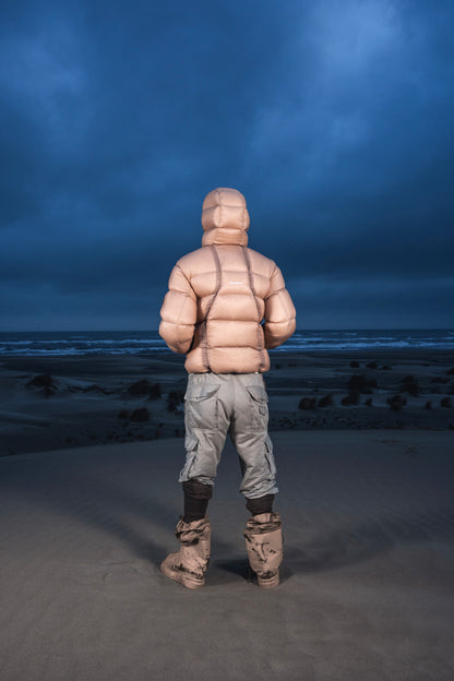 Homme de dos dans les dunes au crépuscule en Alive Puffer Jacket beige