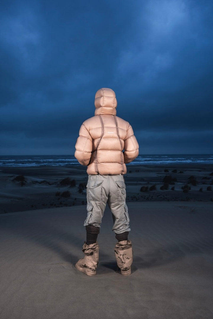 Homme de dos dans les dunes au crépuscule en Alive Puffer Jacket beige