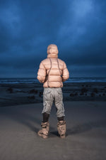 Homme de dos dans les dunes au crépuscule en Alive Puffer Jacket beige