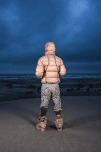 Homme de dos dans les dunes au crépuscule en Alive Puffer Jacket beige