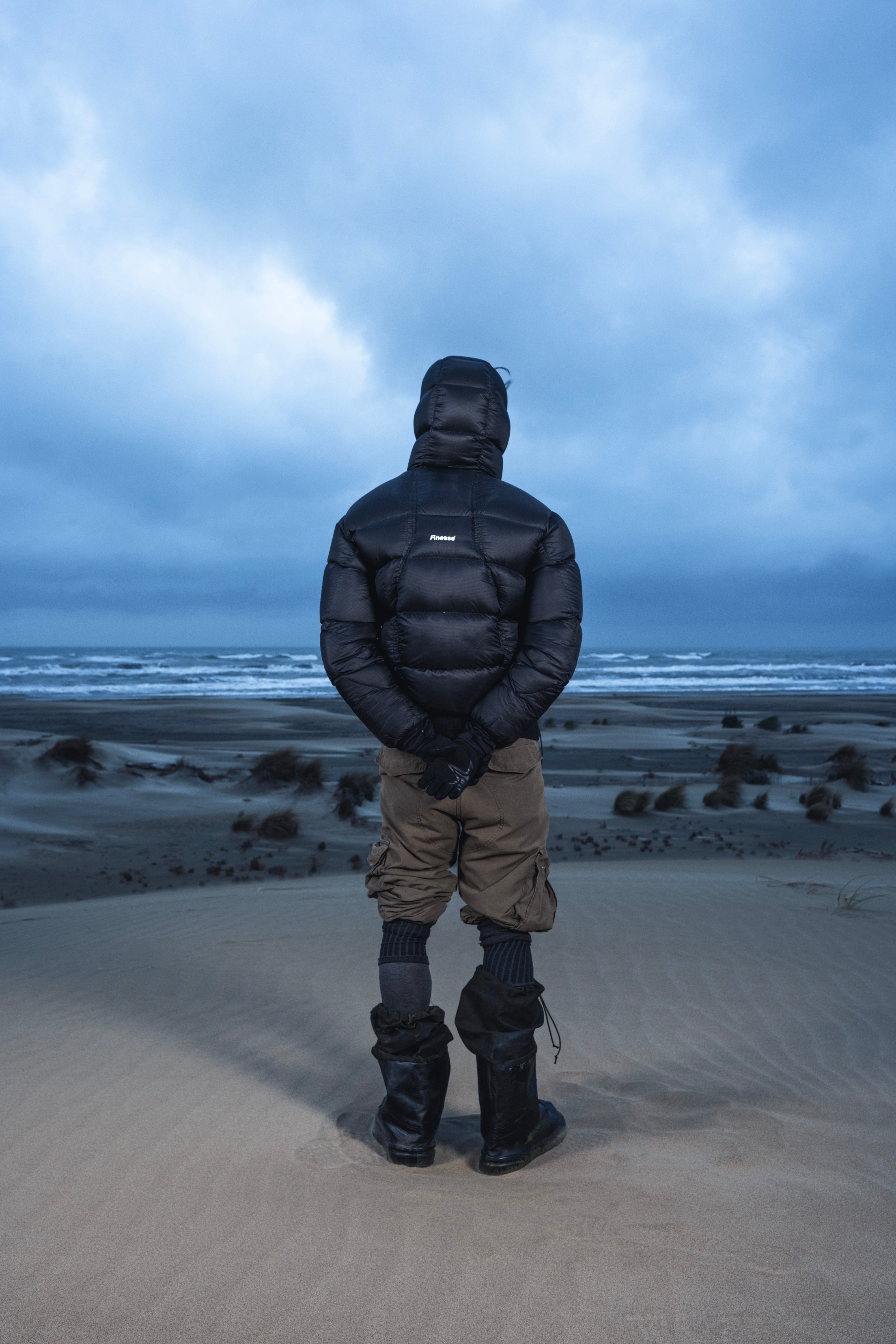 Homme de dos dans les dunes portant la Finesse Alive Puffer Jacket