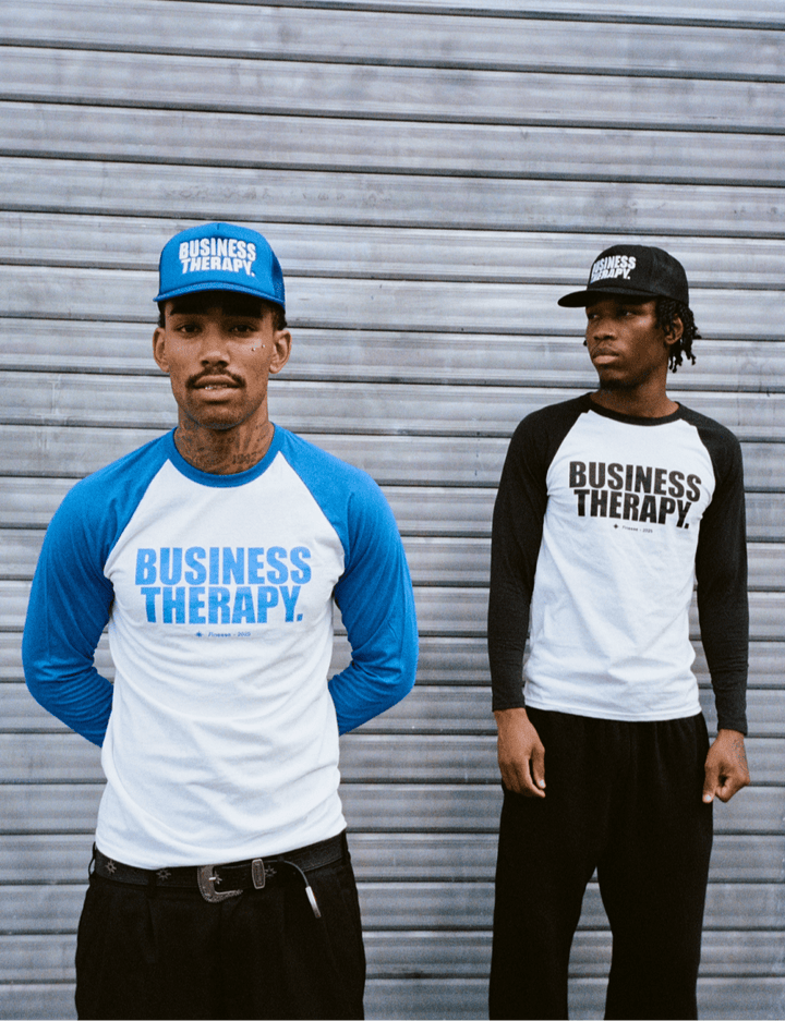 Deux hommes devant rideau métallique en Baseball Tee Business Therapy (bleu & noir) avec casquettes assorties