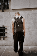 Homme vu de dos devant mur urbain portant le Finesse Black Vanta Backpack.