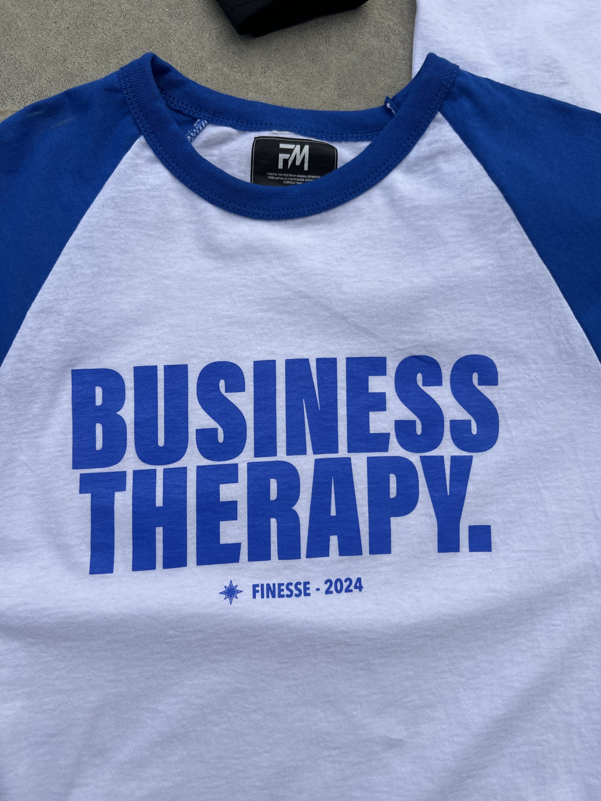Zoom sur l’imprimé Business Therapy d’un Baseball Tee bleu.