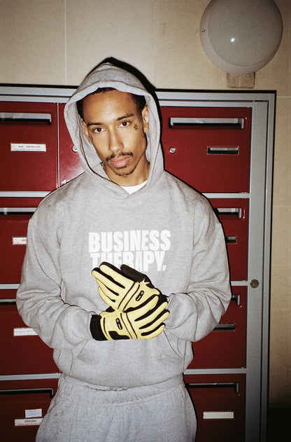 Homme en hoodie Business Therapy gris avec gants Finesse dans cage d’escalier à boîtes rouges.