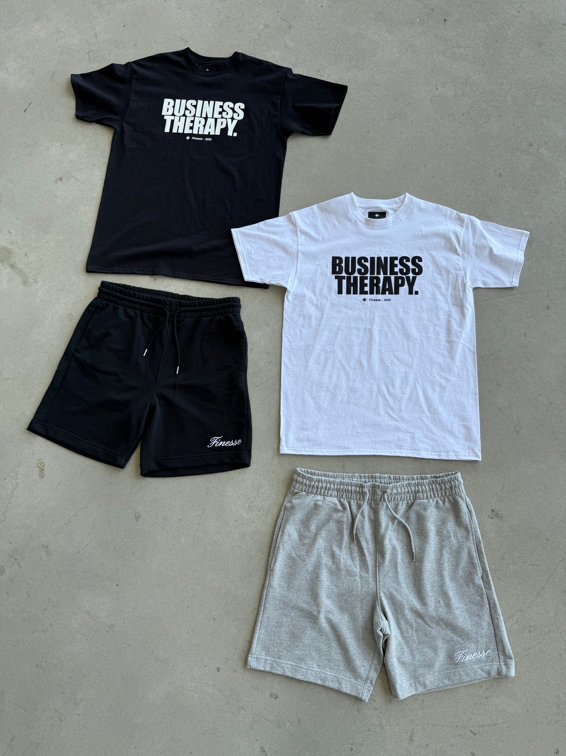 Packshot au sol avec Cotton Shorts noir et gris, associés aux T-shirts Business Therapy noir et blanc