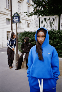 Scène rue Favard à Paris : trois personnes, femme en avant-plan avec capuche portant l’ensemble Air Cotton bleu."