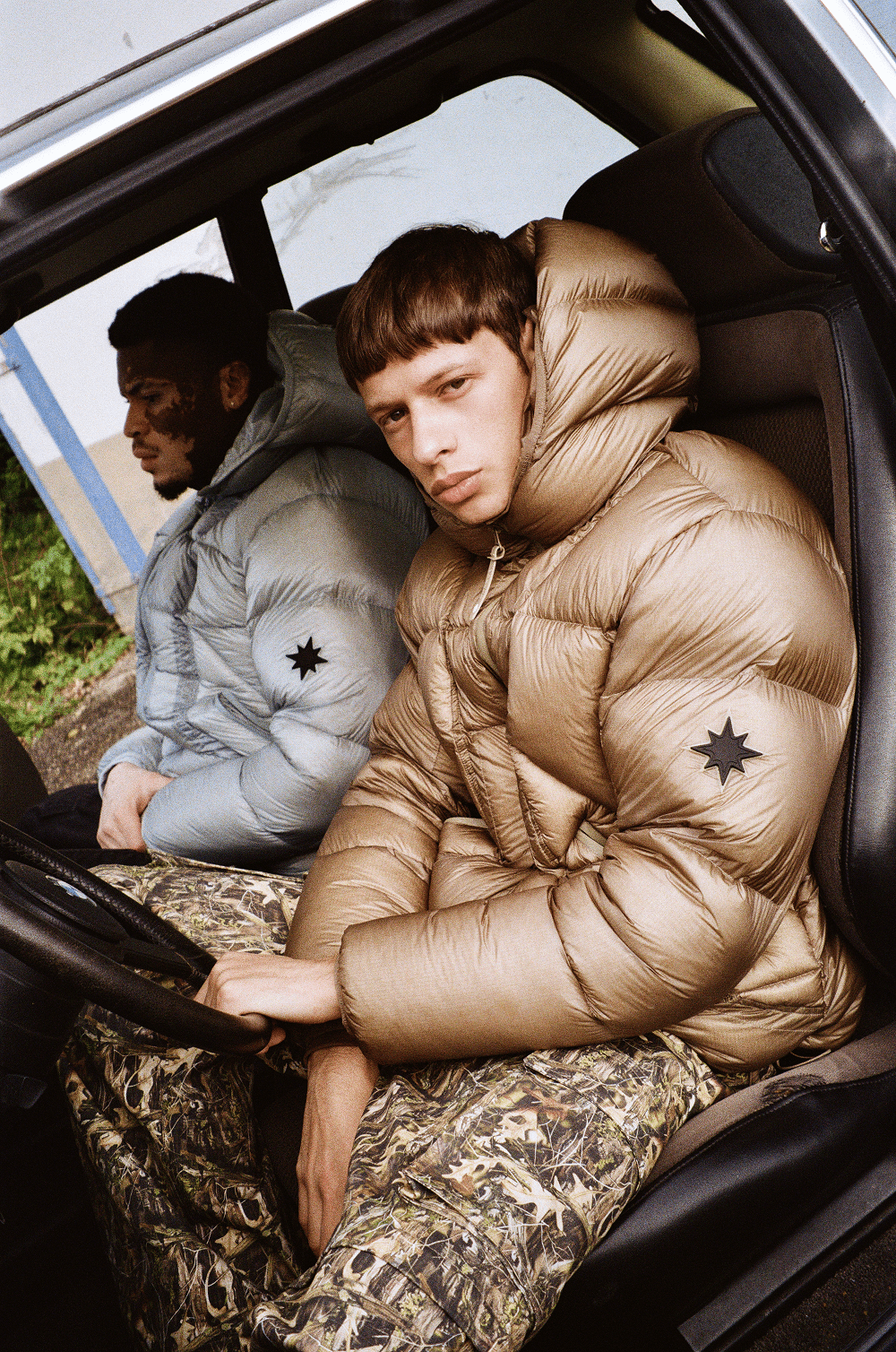 Vue subjective d’un mannequin portant la Finesse* Alive Puffer Jacket Light Bronze au volant d’une voiture.