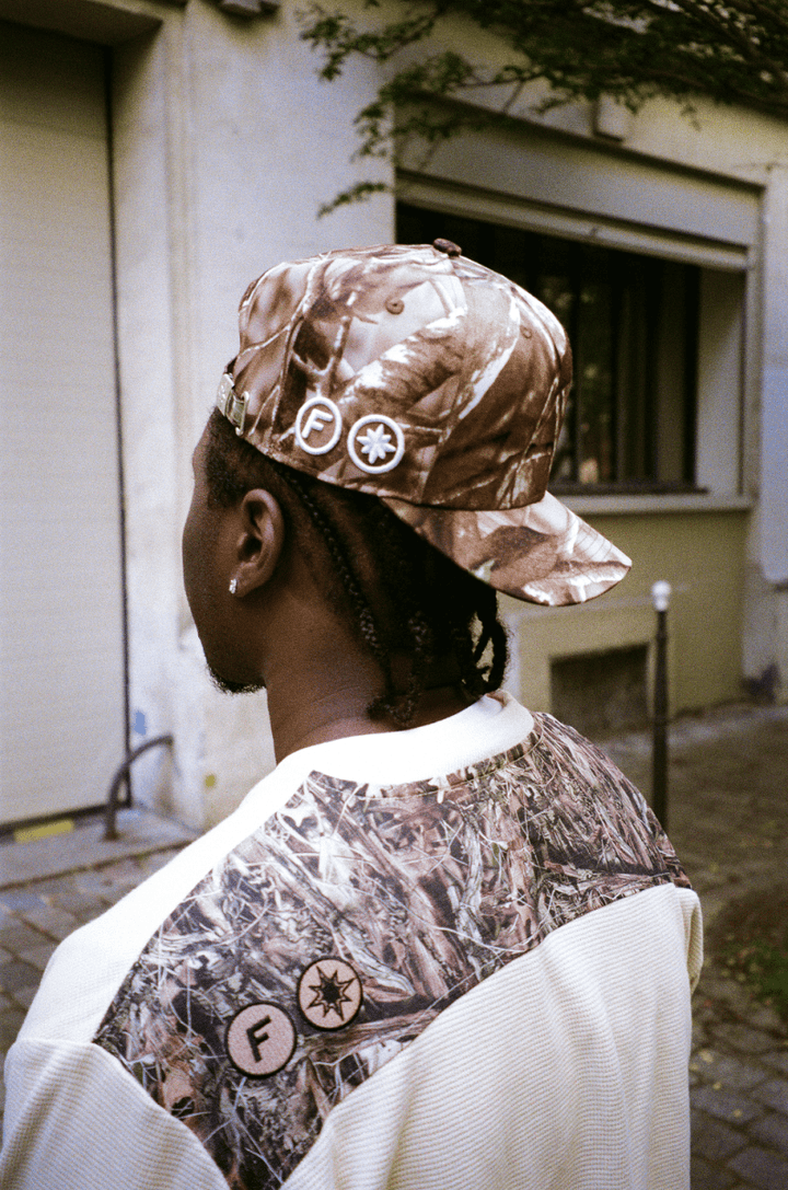 Zoom sur la tête du rappeur 15 KAINZ de dos, portant la Finesse "SIGN" Cap-CAMO à l’envers.
