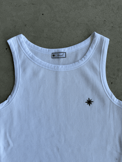 Zoom sur logo pec du Tank Top Finesse blanc posé au sol.