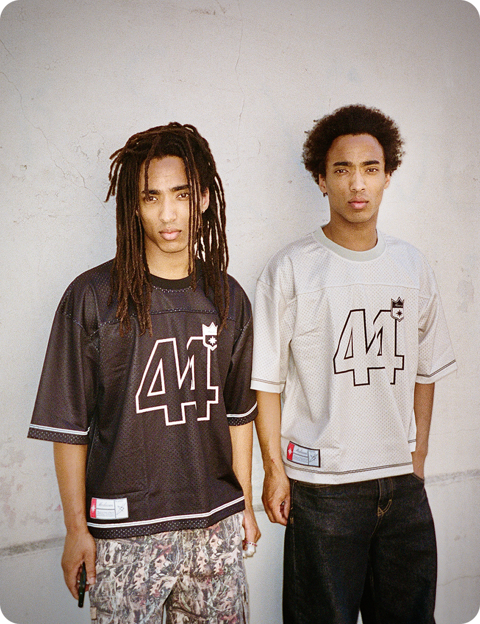 Deux hommes adossés à un mur beige en Jerseys Finesse 44 black et beige