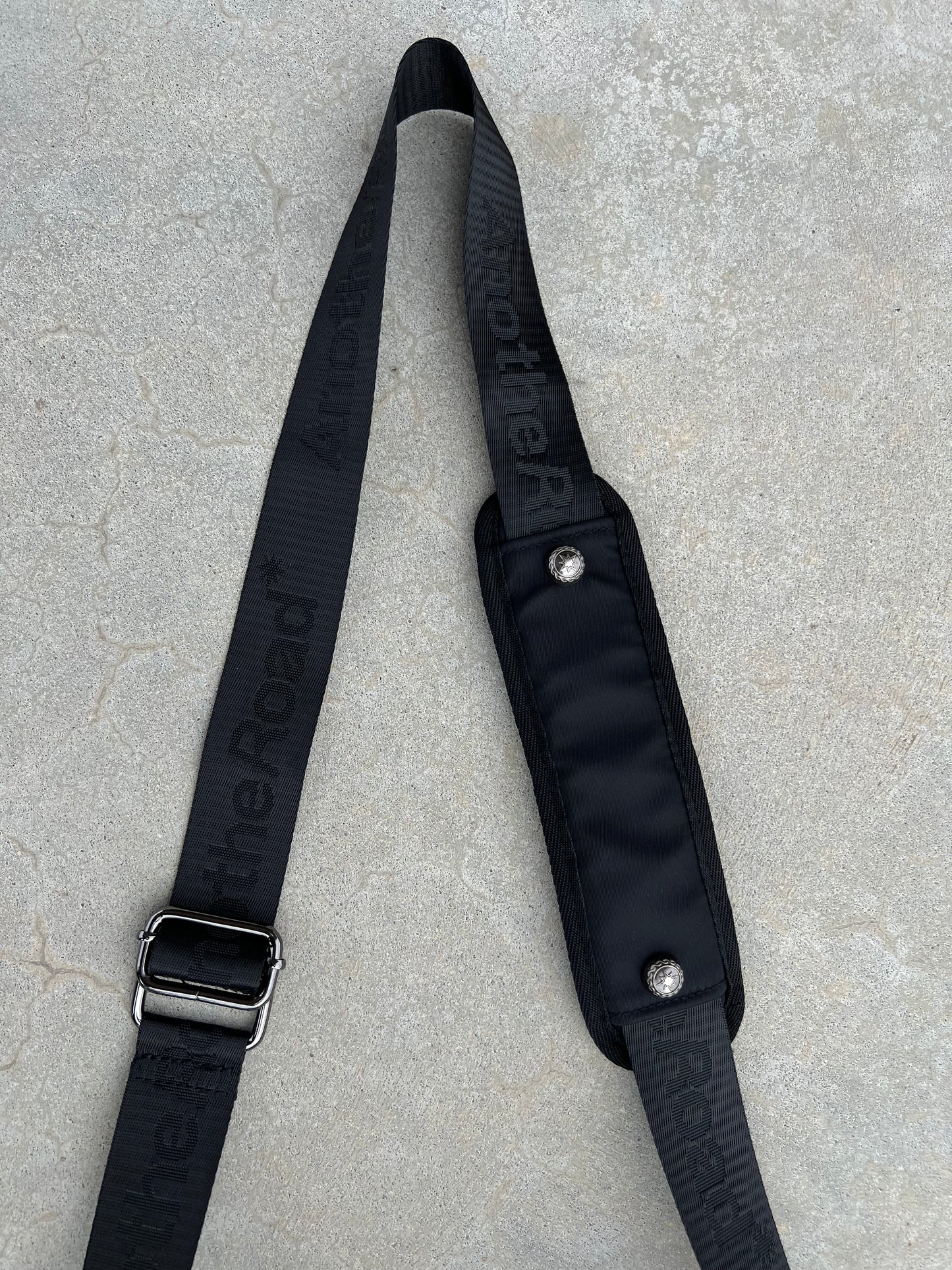 Sacoche Finesse Memorial Bag posée au sol, focus sur la lanière et ses détails