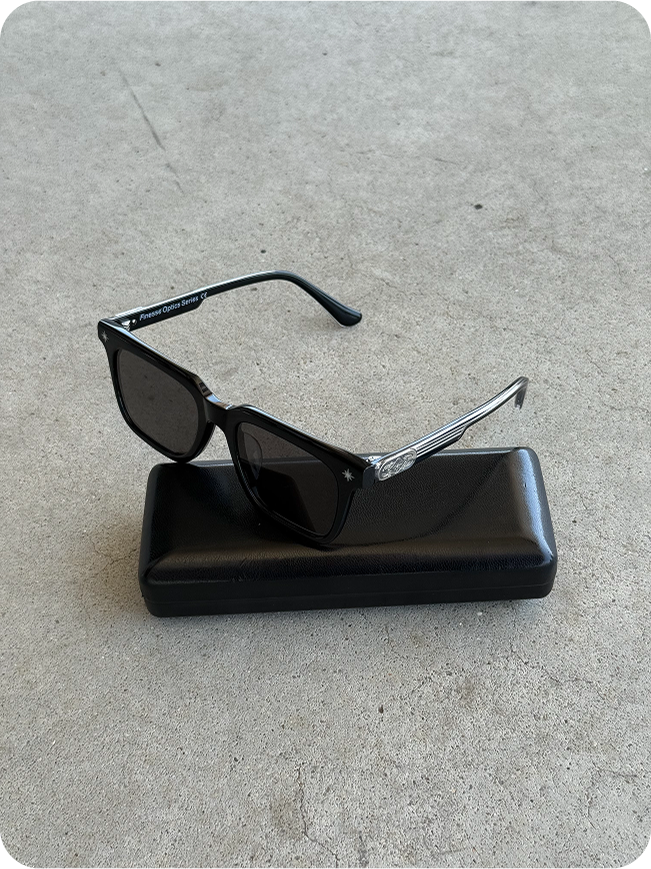 Lunettes Finesse Sunglasses Series 01 avec étui posées au sol en packshot.