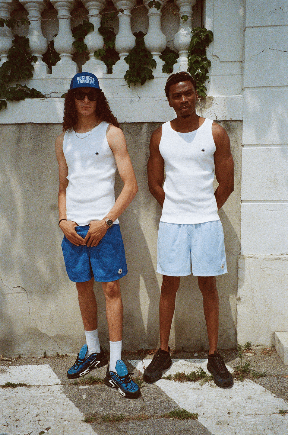 Deux hommes en Swim Shorts et Tank Top, même scène urbaine sous un angle différent.