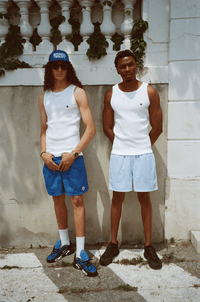 Deux hommes en Swim Shorts et Tank Top, même scène urbaine sous un angle différent.