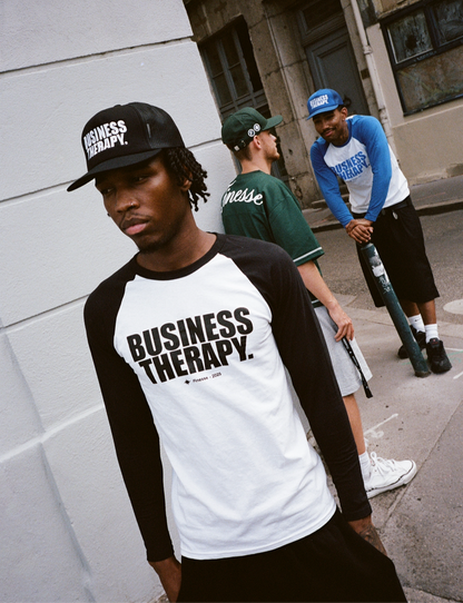 Homme en Trucker Cap noire Business Therapy au premier plan, deux hommes discutent derrière.